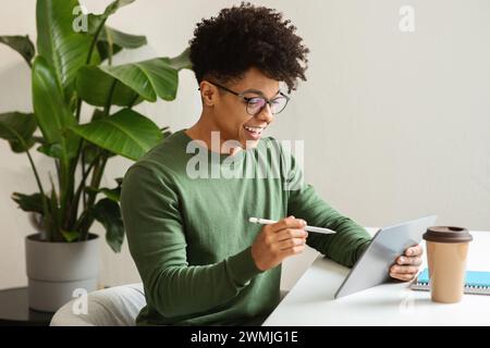 Stylish african american guy using digital tablet, drinking coffee Stock Photo