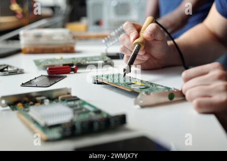 Hands of young unrecognizable technician or engineer with transmission device repairing motherboard of computer processor in service center Stock Photo