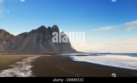 Drone shot of stokksnes beach on shore, vestrahorn mountains on icelandic peninsula with black sand beach. Beautiful nordic landscape scenery on roadside, panoramic view. Slow motion. Stock Photo