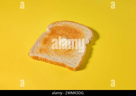 Bread slice, toast with a slice of butter melting, isolated on yellow background, breakfast food Stock Photo