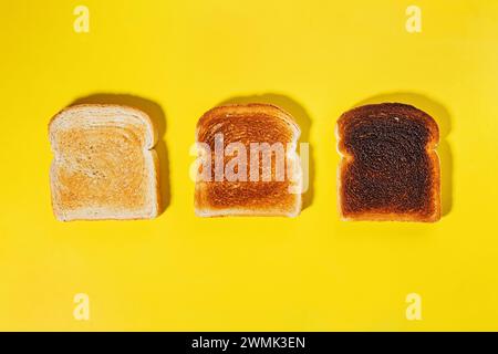 Different stages of toast, toasted square bread slices isolated on yellow background Stock Photo