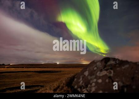 Icelandic highlands with northern lights are visible. Amazing scenery created by aurora borealis under sky full of stars. Stunning natural event with vibrant colors and snow covered rocks. Stock Photo