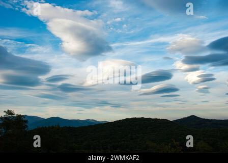Lenticular clouds form over mountains Stock Photo