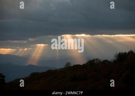 Sunlight streams through breaks in the grey clouds over the Blue Ridge Mountains at twilight; North Carolina, United States of America Stock Photo
