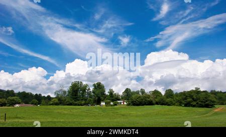 White clouds against a blue sky over houses and green fields; North Carolina, United States of America Stock Photo