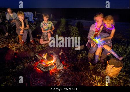 Family gathers around a campfire at the Valparaiso pond in Valparaiso, Nebraska; Valparaiso, Nebraska, United States of America Stock Photo