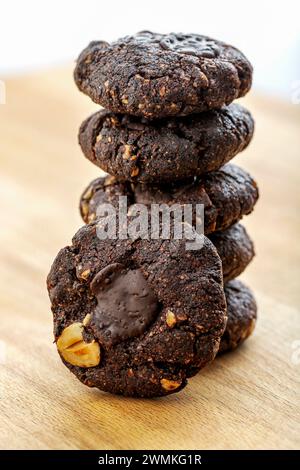 Close-up of a stack of chocolate nut cookies on a wooden board; Studio Shot Stock Photo