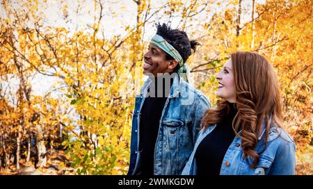 Mixed race married couple, smiling as they walk through a city park during a fall family outing, spending quality time together Stock Photo