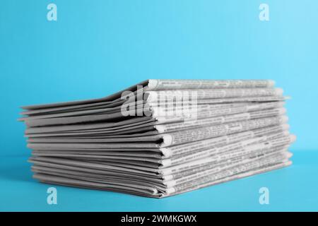 Stack of newspapers on light blue background. Journalist's work Stock Photo