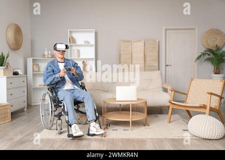 Happy young man in wheelchair using VR glasses at home Stock Photo