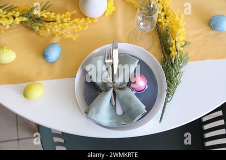 Festive table setting decorated with mimosa flowers and Easter eggs Stock Photo