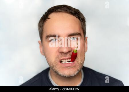 Portrait of young man eating chili pepper. red hot pepper in the mouth close-up Stock Photo