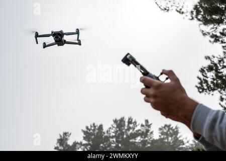 Photograph of man's hands holding the remote control of a Drone (Drone Operator). Technology concept. man is having fun with a quadcopter in nature. c Stock Photo