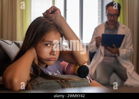 Child psychologist working with upset worried girl in office or at home, scared teen turning back, feeling anxiety while talking with specialist durin Stock Photo