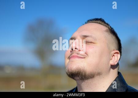 Young attractive man enjoying the sun in a park with eyes closed Stock Photo