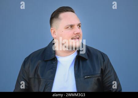 Young attractive man in his twenties in a black leather jacket looking in to the distance Stock Photo