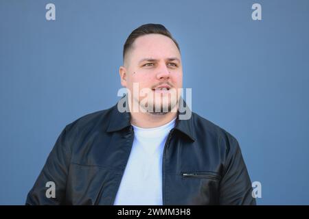 Young attractive man in his twenties in a black leather jacket looking in to the distance Stock Photo