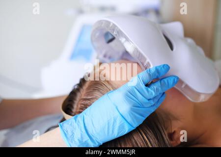 Close-up image of a patient receiving a state-of-the-art LED facial mask treatment in a beauty clinic. Horizontal photo Stock Photo