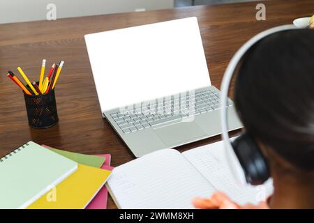 Biracial girl studying at home using a laptop, with copy space Stock Photo