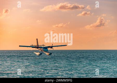 Exotic scene seaplane on Maldives sea landing. Seaplane landing on sunset sea. Vacation or holiday in Maldives concept background. Air transportation Stock Photo