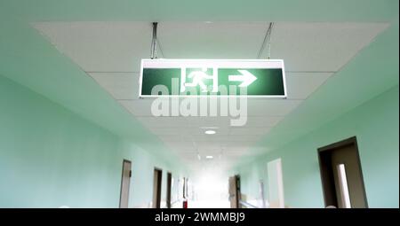 Exit sign suspended from the ceiling of hospital corridor Stock Photo