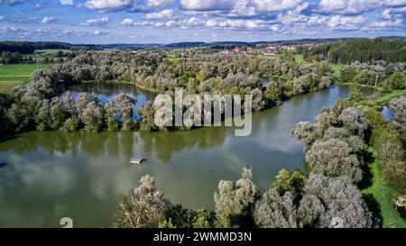 Aerial view of a serene pond surrounded by lush green meadows, dense ...