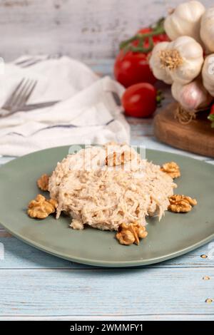 Circassian chicken dish. Appetizer dishes. Salad with flour, walnuts and chicken on a blue wooden background. local name çerkez tavuğu. Close up Stock Photo