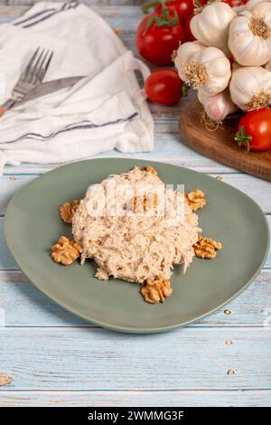 Circassian chicken dish. Appetizer dishes. Salad with flour, walnuts and chicken on a blue wooden background. local name çerkez tavuğu Stock Photo