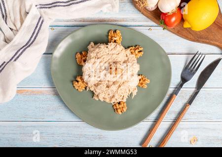 Circassian chicken dish. Appetizer dishes. Salad with flour, walnuts and chicken on a blue wooden background. local name çerkez tavuğu. Top view Stock Photo