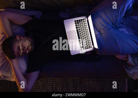 Tired businessman sleeping on sofa at home with laptop, top view. Stock Photo
