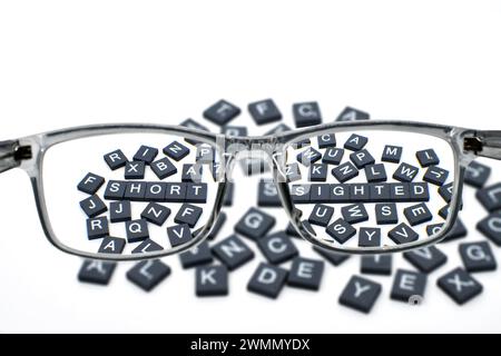 Words short sighted viewed through a pair of glasses for long distance vision. Eyesight correction concept. Stock Photo