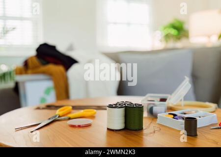 Spools of thread and basic sewing tools including pins, needle, a thimble, and tape measure Stock Photo