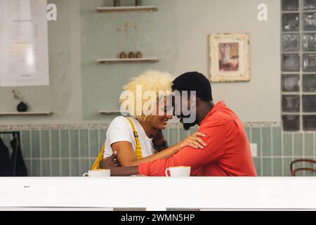A diverse biracial couple shares a tender moment at a cafe Stock Photo
