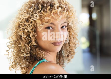 Young biracial woman smiles gently at home Stock Photo