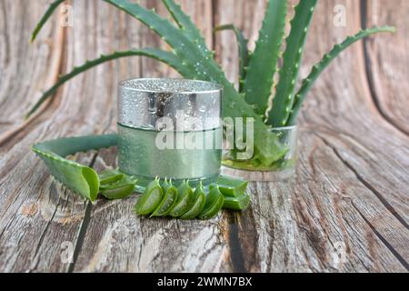 Fresh aloe vera leaves, cosmetic cream with aloe vera extract in glass container on wooden background. Natural cosmetics concept. For Health and beaut Stock Photo