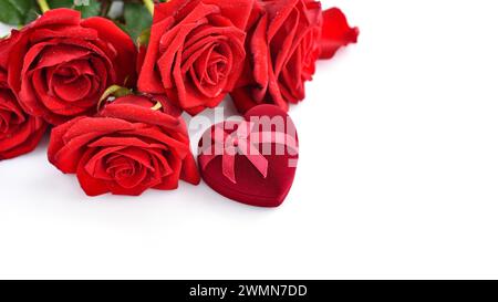Red rose bouquet with heart-shaped gift box on white background. For greeting card or banner. Soft focus Stock Photo