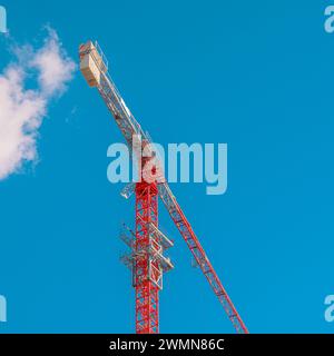 A red construction crane against sky with cloud entering it. Stock Photo