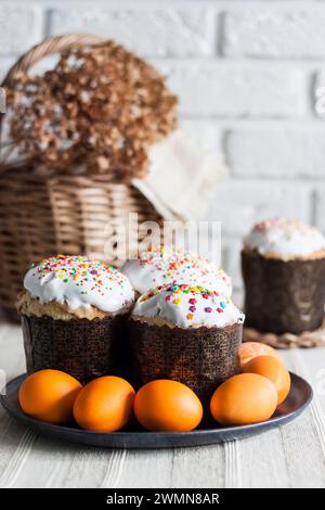 Glaze decorated Easter cakes and yellow colored eggs on a plate closeup. Stock Photo