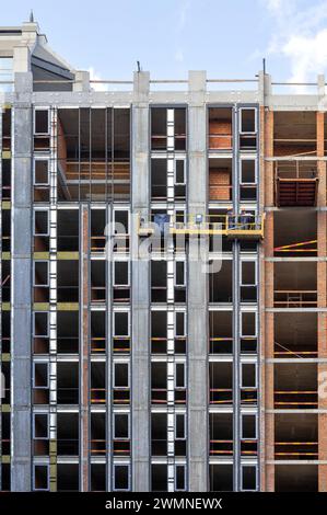 Fragment of the construction of a residential building using a construction cradle on a sunny day. Stock Photo