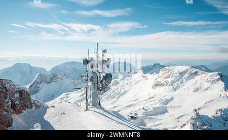Antennas of communication equipment at the top of snow-covered alpine summit. Telecommunication tower up high in the mountains. Stock Photo