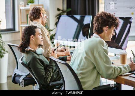 Young man with headphones editing photos on tablet and looking at monitor in startup office Stock Photo