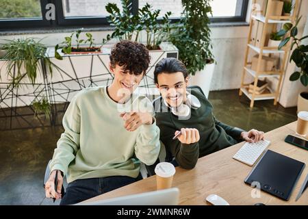 Coworkers collaborating on retouching tasks in post-production office, happy young men in 20s Stock Photo