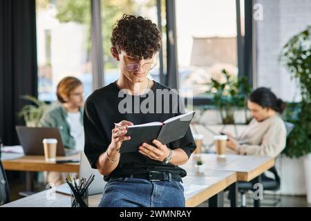 Curly-haired man with glasses taking notes in a dynamic office space, planning startup Stock Photo