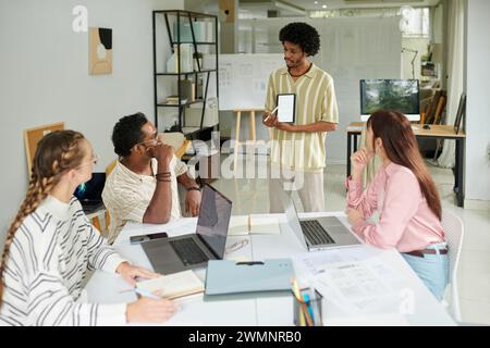UI designer showing wireframe of mobile application in meeting with colleagues Stock Photo