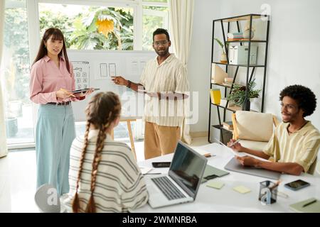Team of UI designers talking in front colleagues in meeting, presenting ideas Stock Photo