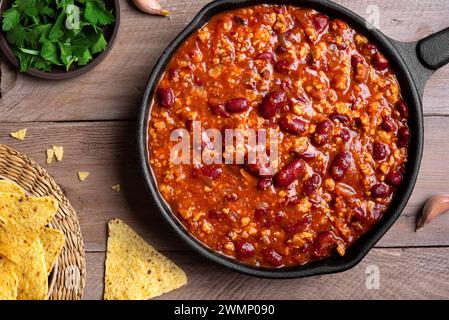 Chili con carne in pan on wooden background, top view. Homemade mexican food concept, chili with red beans and ground beef, protein fiber meal. Stock Photo