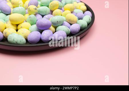 Colourful easter eggs in black plate on pink background. Creative easter composition, spring, copy space. Stock Photo