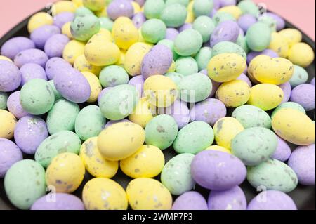 Colourful easter eggs in black plate on pink background. Creative easter composition, spring, copy space. Stock Photo