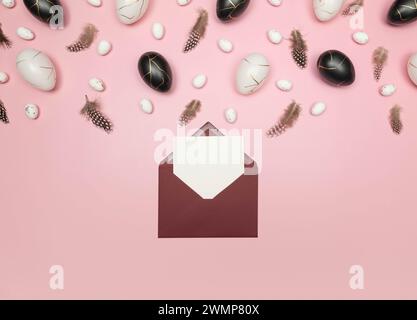 Top view of easter eggs, feathers, red envelope and white card on pink background. Creative easter composition, spring, flat lay, copy space. Stock Photo