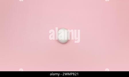 Top view of one white egg on pink background. Creative easter composition, flat lay, copy space. Spring, modern and minimalist. Stock Photo